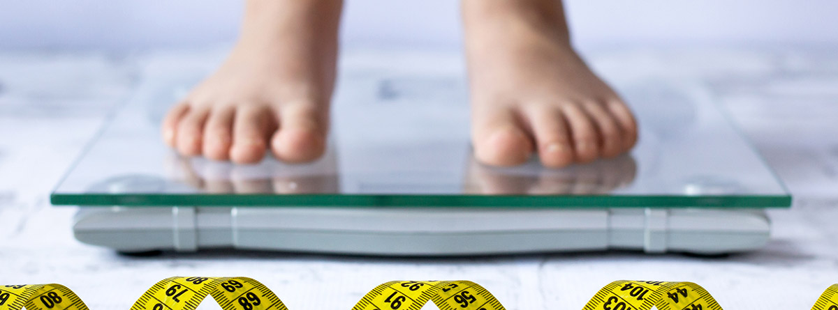 Malnutrición en niños: pies de niño encima de una báscula y trozos de cinta de metro