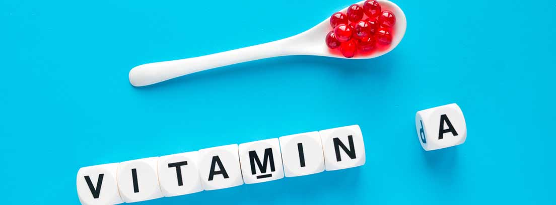 cuchara con cápsulas y cubos blanco con la palabra vitamina A