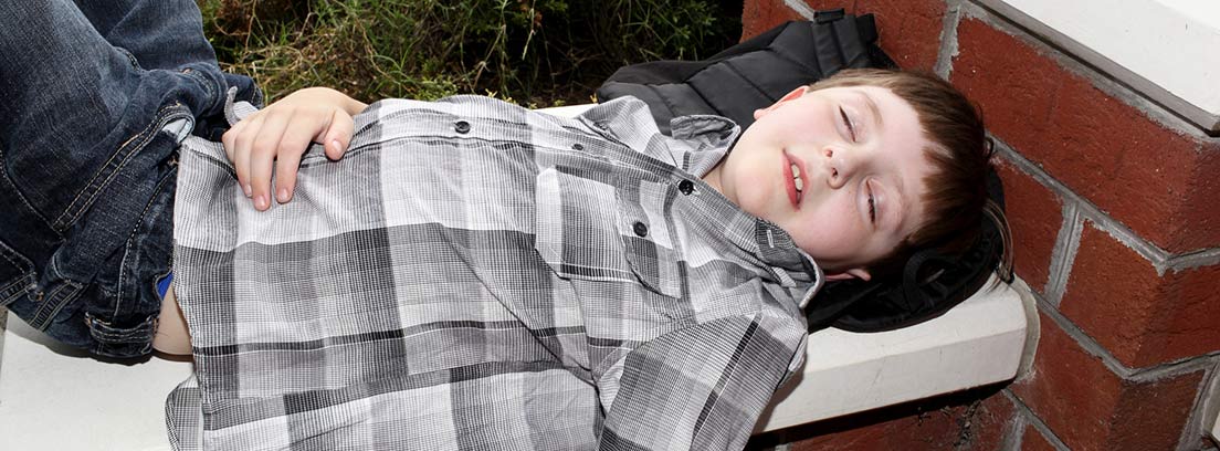 niño tumbado sobre un banco de piedra