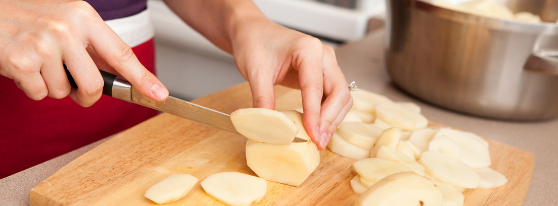 mujer cortando patatas crudas