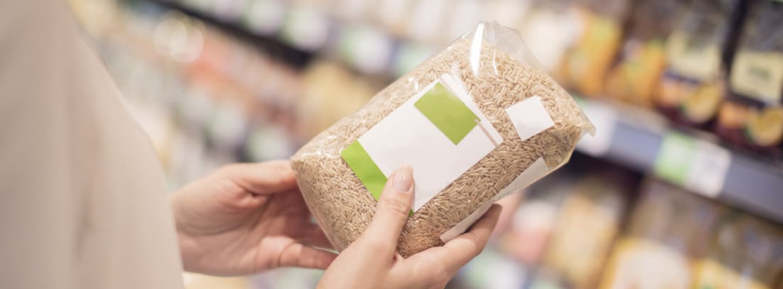 Consejos para comprar productos sanos: mujer con una bolsa de cereales mirando la etiqueta