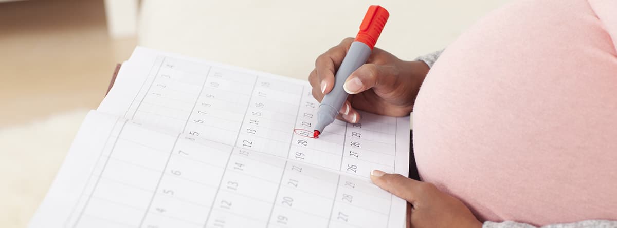 Fecha aproximada del parto: mujer embarazada poniendo en un calendario la fecha aproximada del parto
