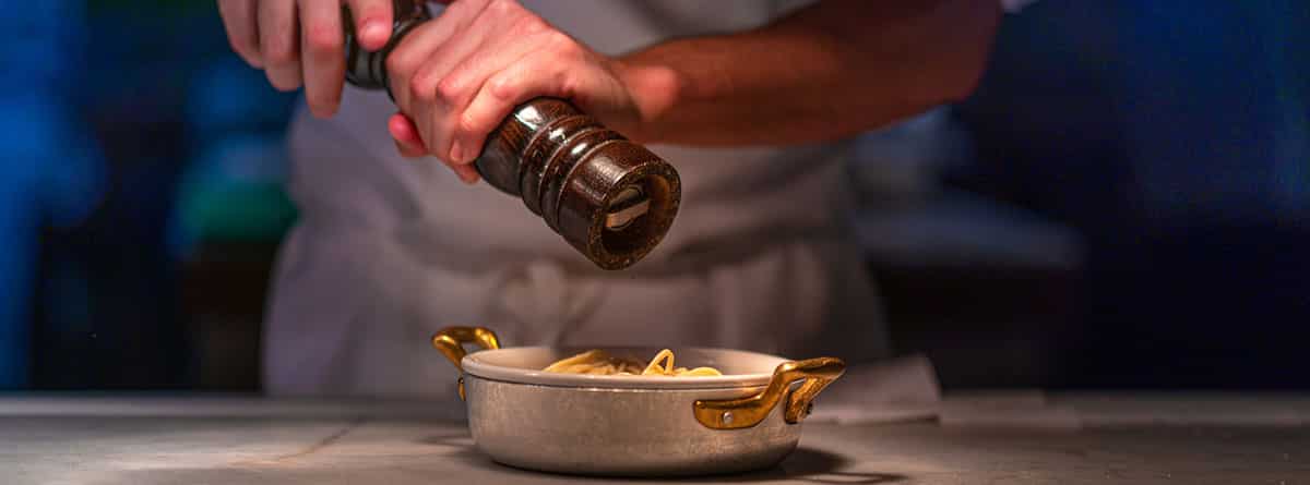 Beneficios de la pimienta: manos echando pimienta a la comida