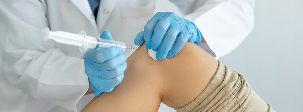 Bultos en la rodilla: especialista en medicina realizando una infiltración en la rodilla de un paciente