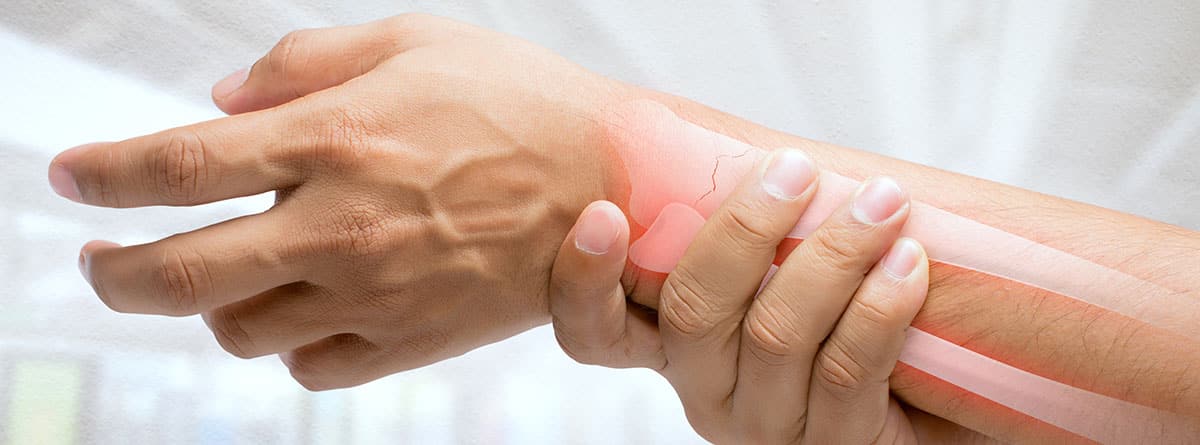 Hombre masajeando muñeca dolorosa sobre un fondo blanco. 