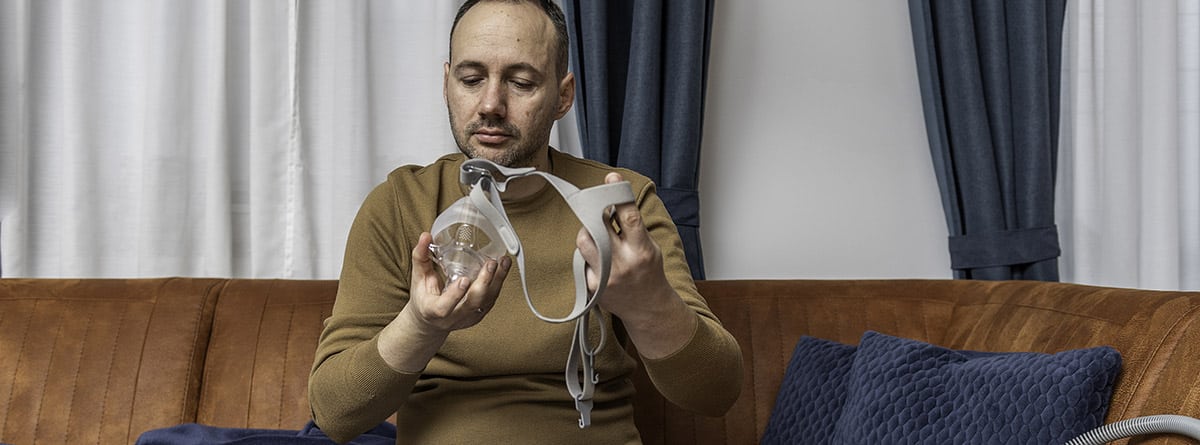 hombre con una mascarilla de oxígeno en la mano