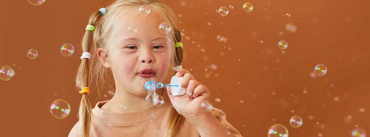 Niña con Síndrome de Down haciendo burbujas.