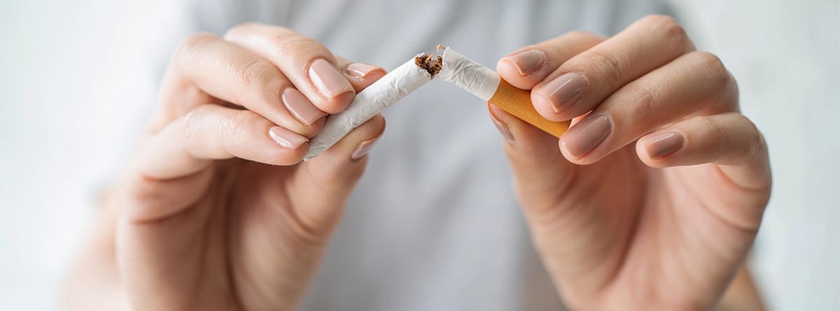 Mujer rompiendo un cigarro por la mitad
